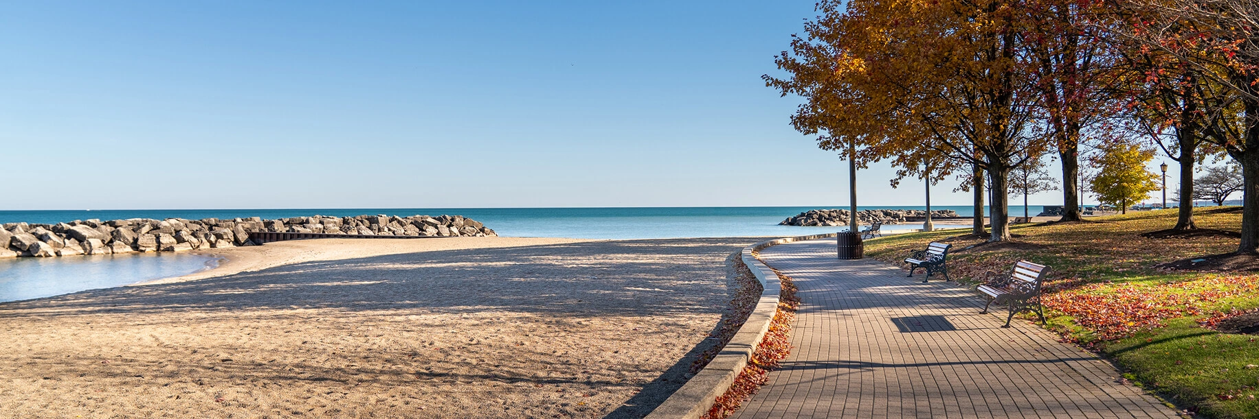 Sidewalk with a view of water and trees changing colors